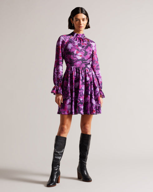 SAMMIEH-Dresses-Hello, gorgeous. SAMMIEH is the ultimate in flirty flower power. Featuring frills, cut outs and a vibrant floral print, this mini dress is just as at home with chunky boots as it is with sky high heels.The fabric of this product is made of 100% recycled polyester. Using recycled polyester helps divert plastic waste from ending in landfills and helps us to reduce our dependancy on virgin materials. Mini dress Floral print Fit and flare Long sleeved with frill cuffs High neck Zip fastening Tie